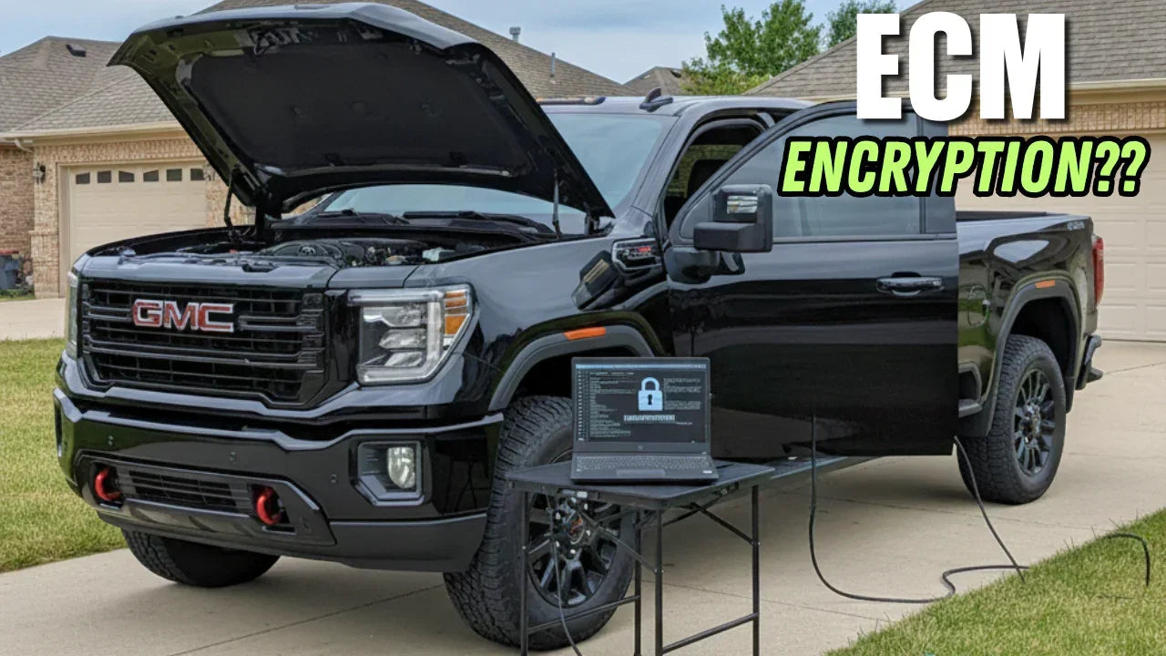 Black GMC pickup truck with hood open, laptop showing ECM encryption graphic on table nearby.