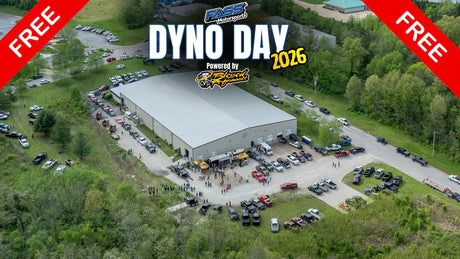 Aerial view of a large event at a warehouse with many trucks, people, and 'Dyno Day 2026' banners.