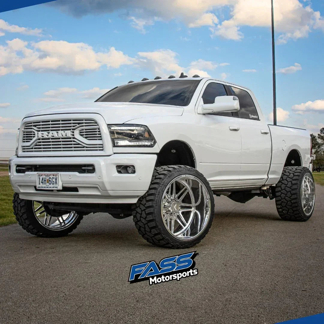 Lifted white RAM truck with large off-road tires and chrome wheels parked outdoors