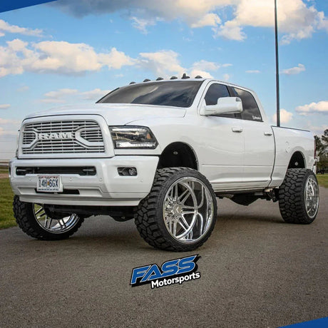 Lifted white RAM truck with large off-road tires and chrome wheels parked outdoors