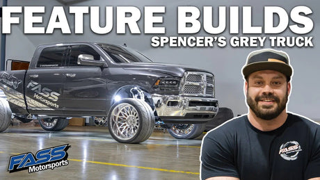 Custom grey pickup truck with FASS Motorsports logo, large chrome wheels, and man in cap