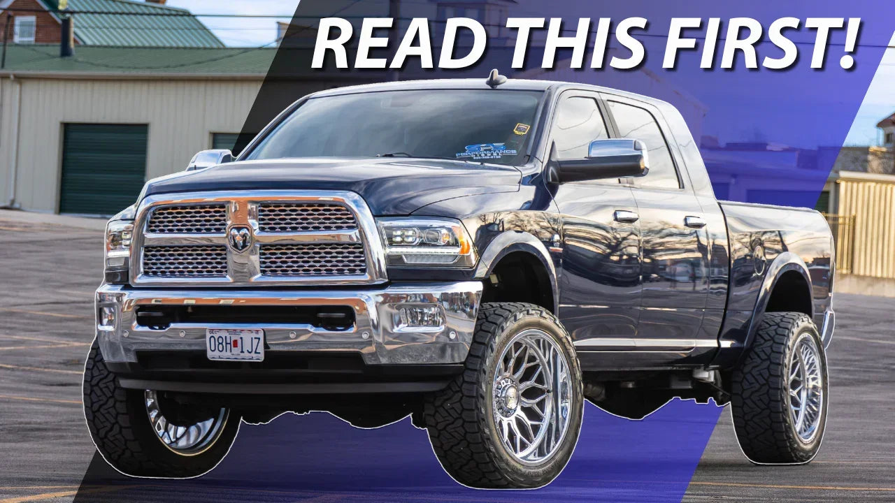 Lifted black pickup truck with chrome grille and large off-road tires parked outdoors.