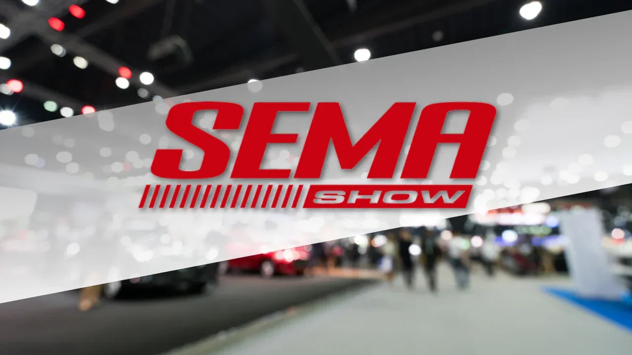 SEMA Show logo over blurred automotive trade show event with lights and people in background