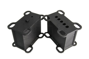 A pair of black metal heavy duty lift blocks for a vehicle, featuring multiple holes for mounting and configuration adjustments.
