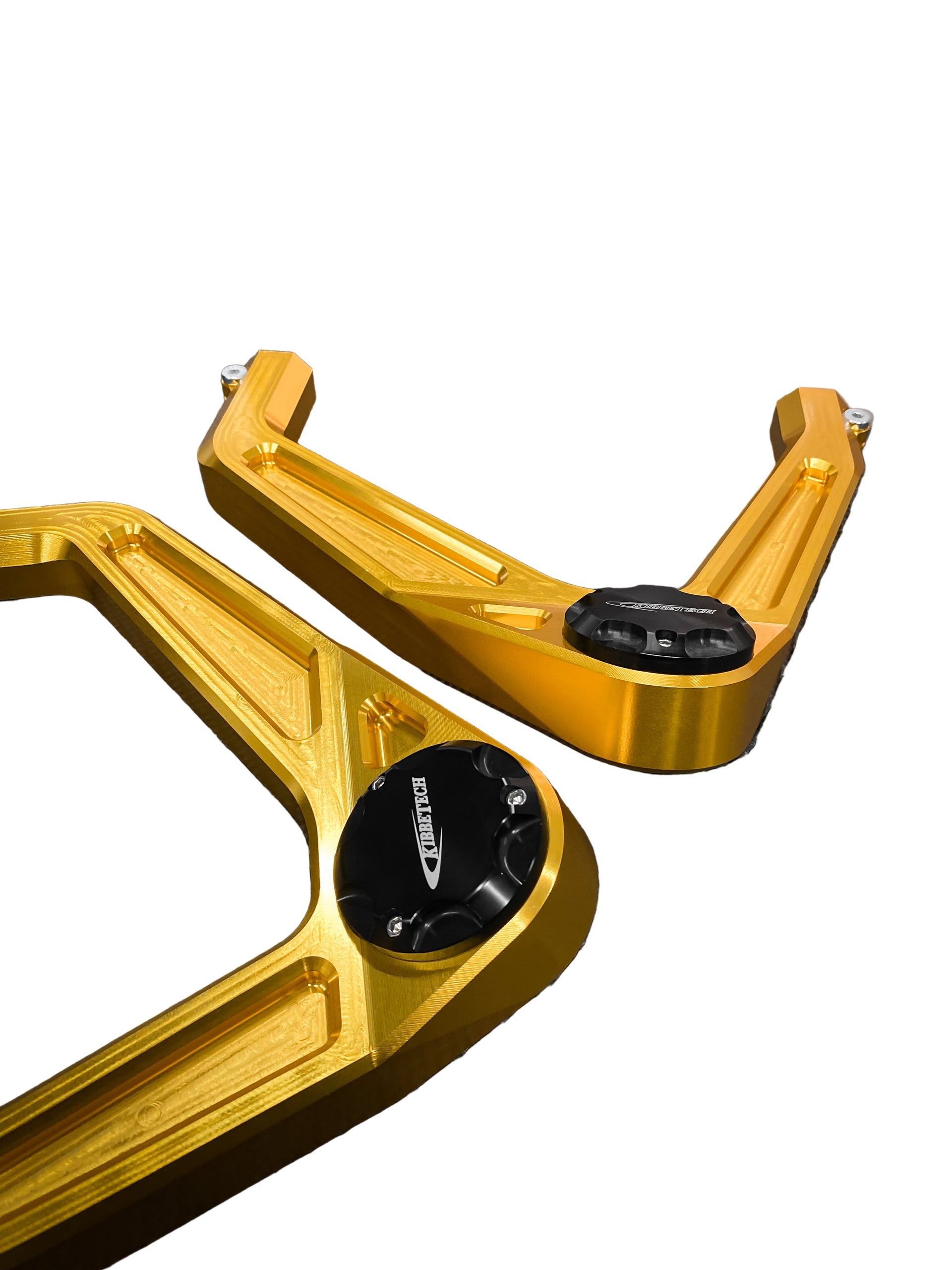 Gold anodized billet upper control arms for a vehicle, displayed on a textured surface.